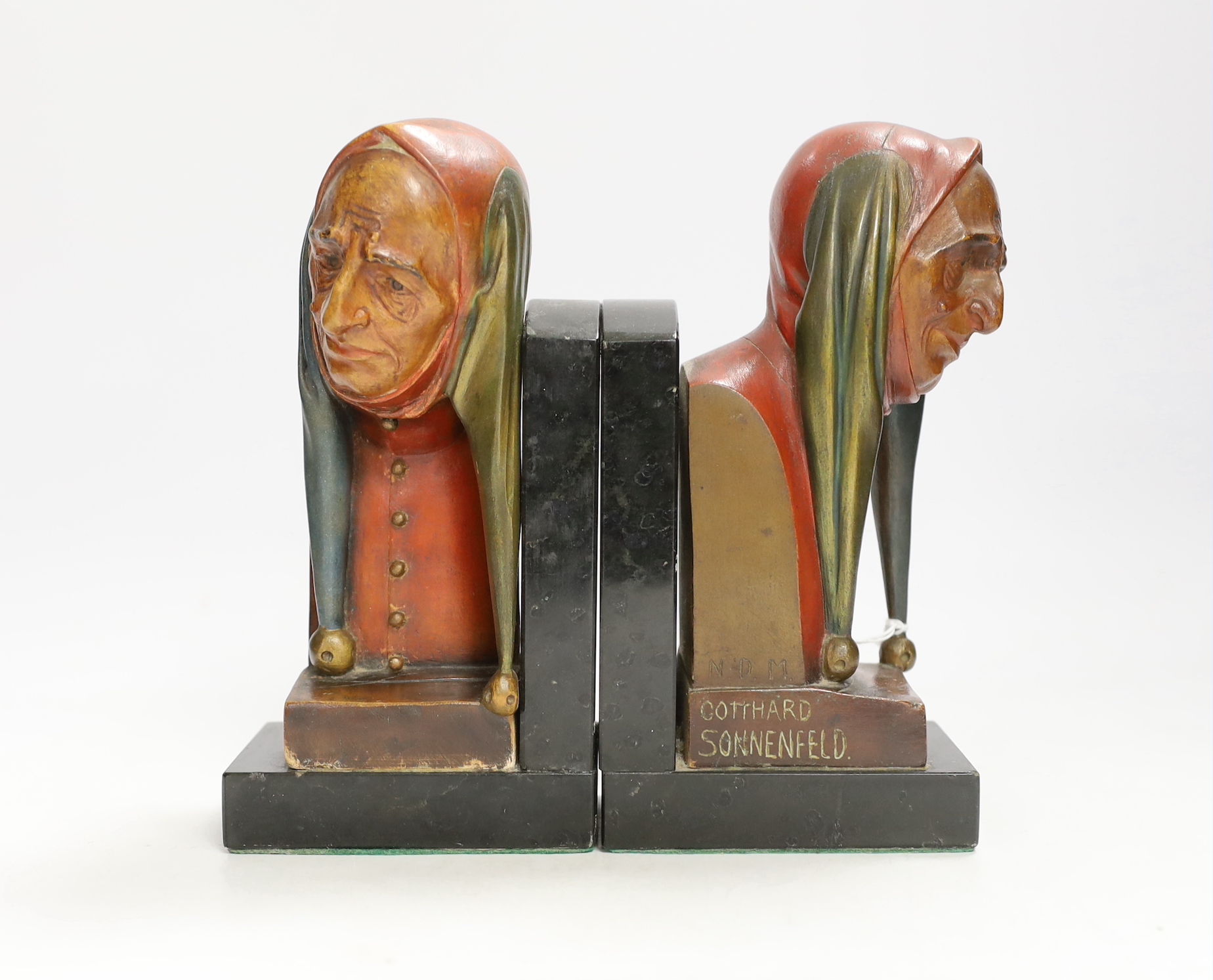 A pair of Gotthard Sonnenfeld painted wood bookends, granite bases, engraved, N.D.M, both with busts of jesters, 20cm high